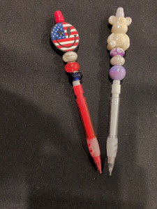 A pencil with beads and a button on it.